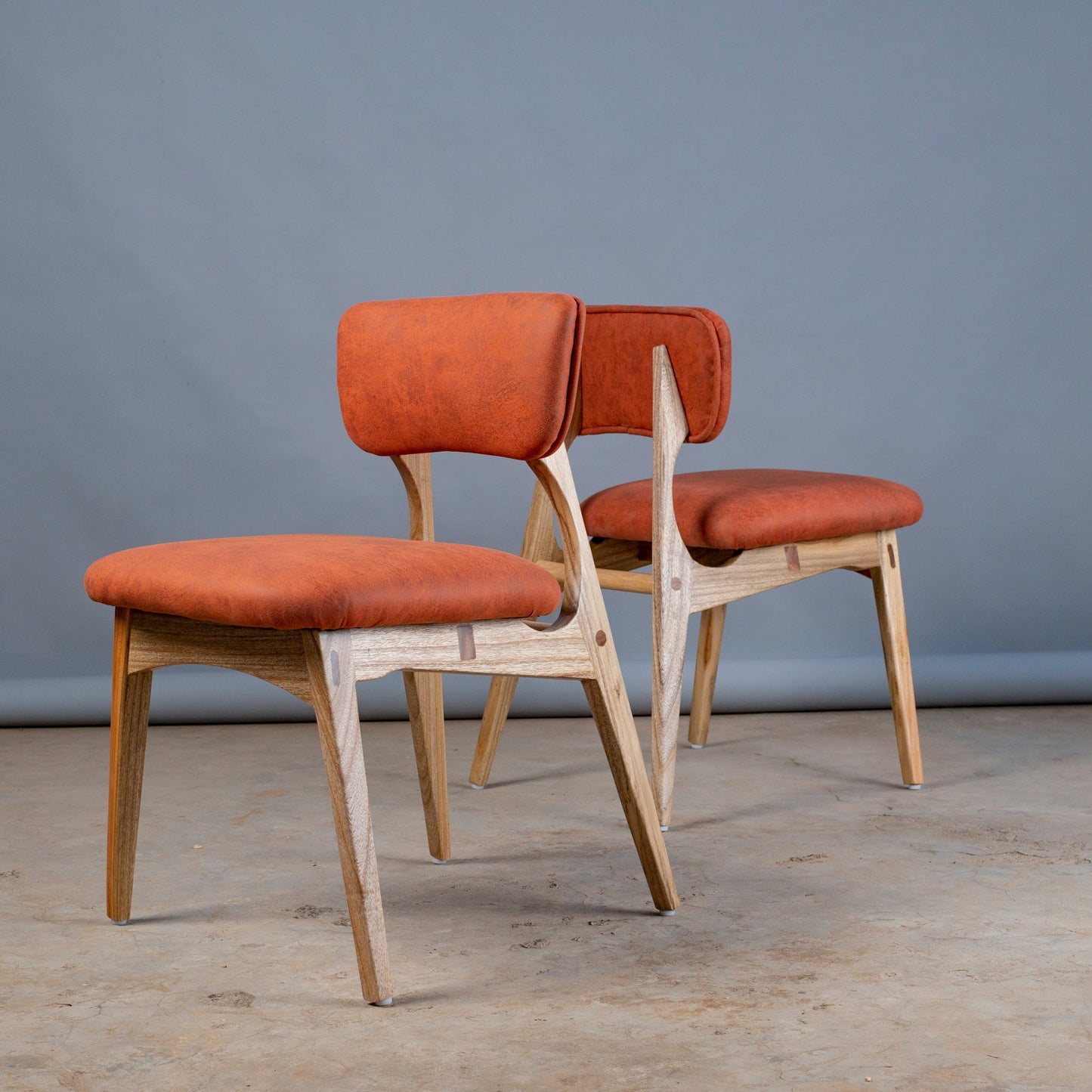 Two chairs with orange seats and backs against a gray background