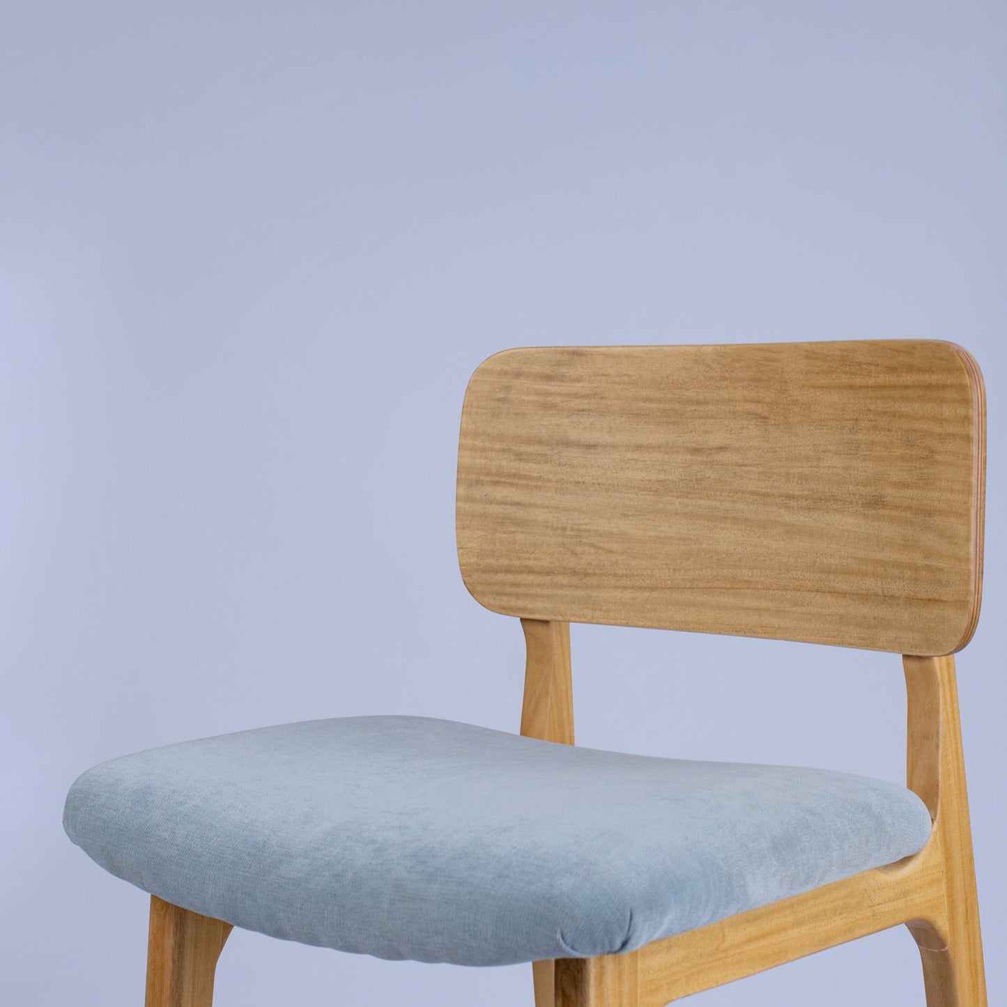 Chair with wooden frame and light blue cushion on a plain background
