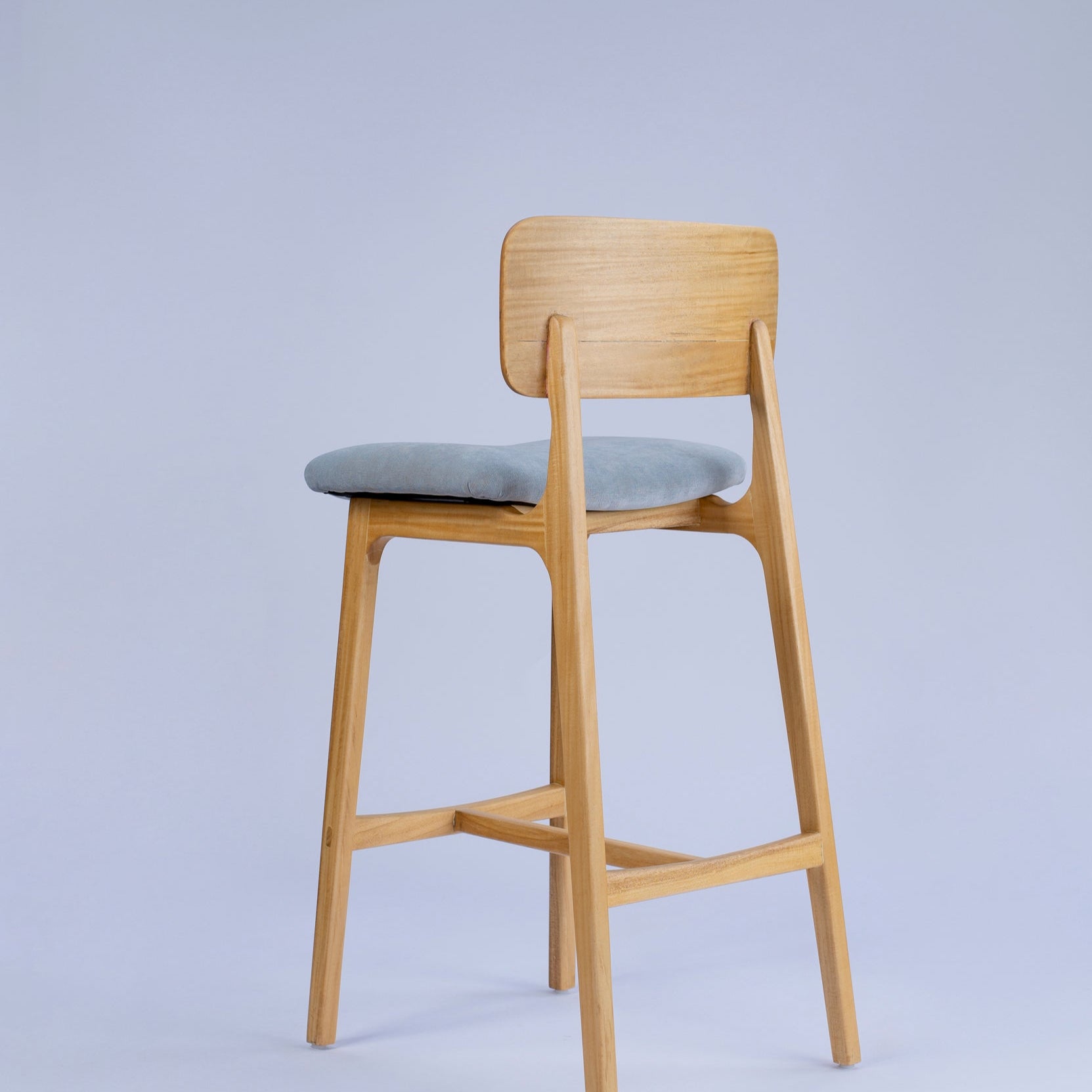 Wooden bar stool with a gray cushion on a light gray background