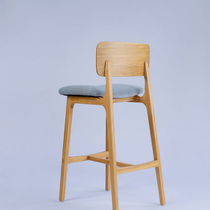 Wooden bar stool with a gray cushion on a light gray background