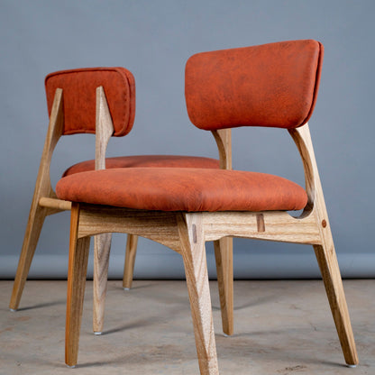 Two orange cushioned chairs with wooden frames on a gray floor.