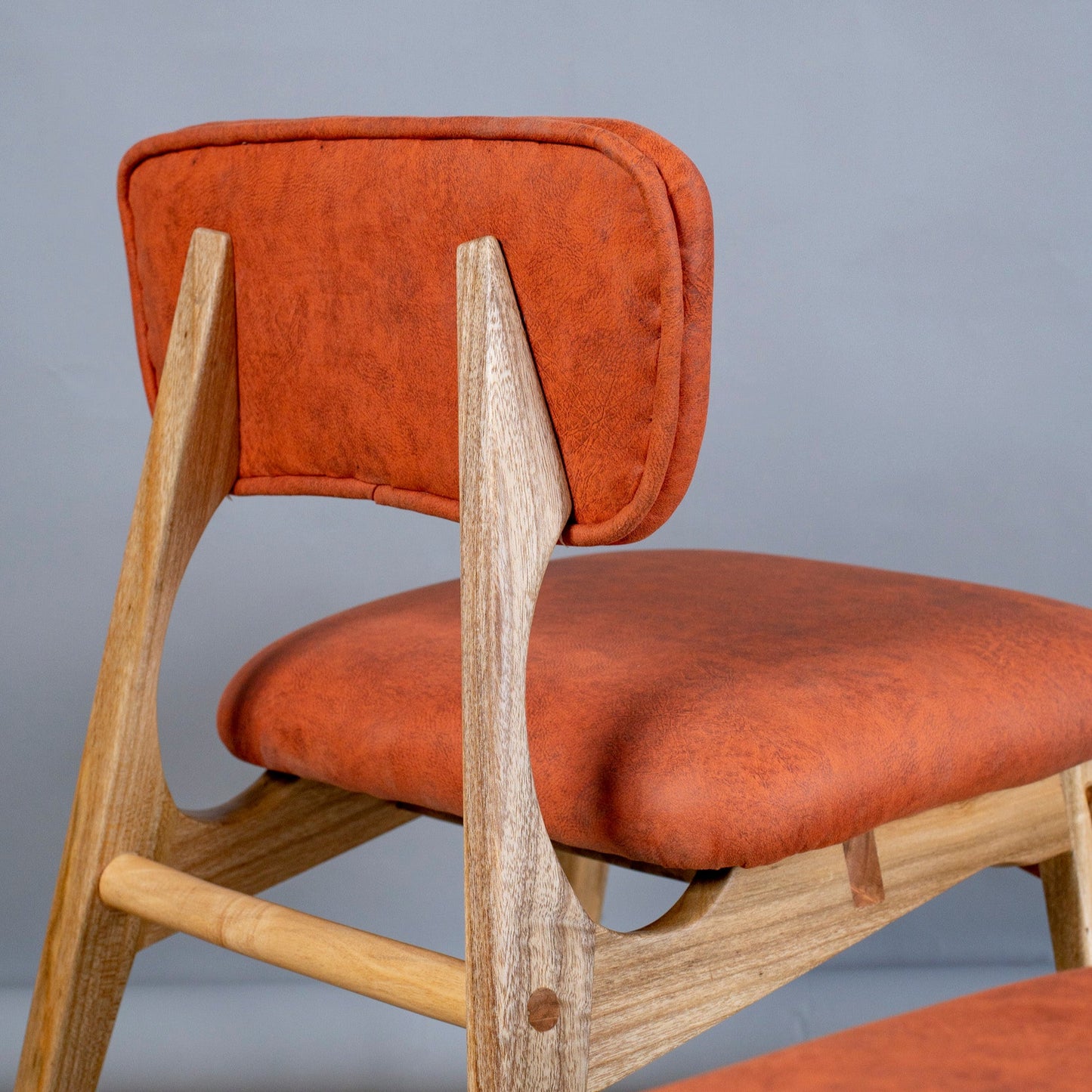Chair with orange cushioned seat and backrest on a plain background