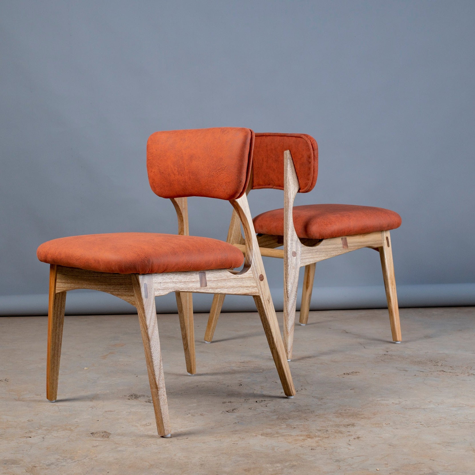 Two chairs with orange seats and backs against a gray background