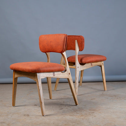Two chairs with orange seats and backs against a gray background