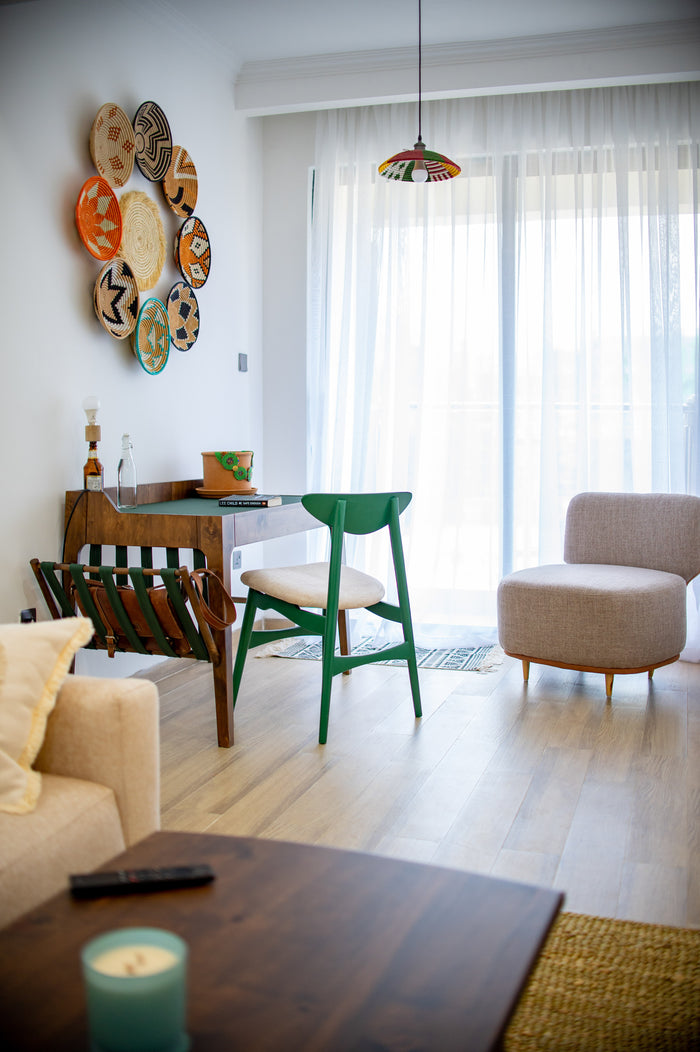Modern living room with a green chair, beige sofa, and decorative wall art.