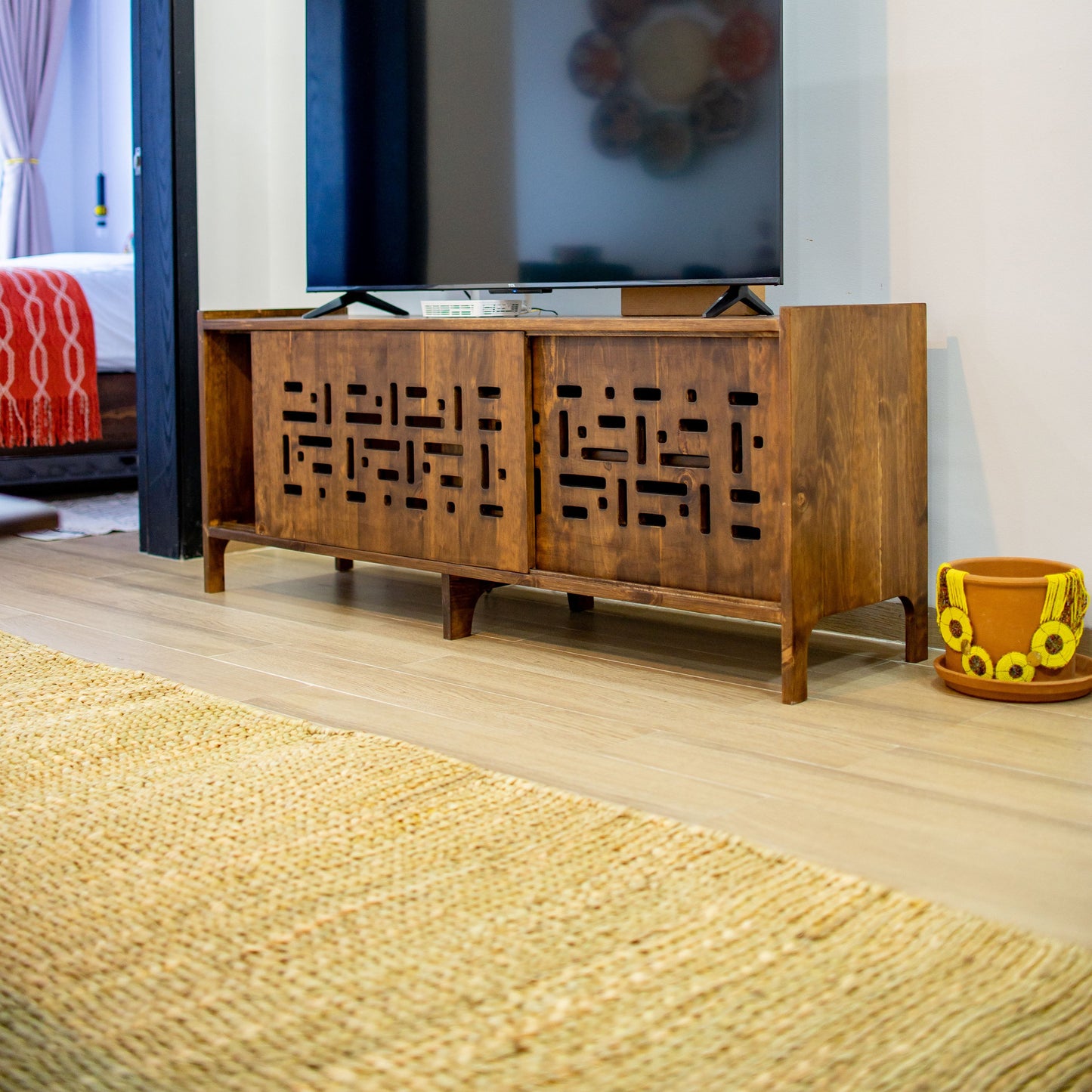 Wooden TV stand with a television displaying a colorful abstract pattern in a living room. By The Seating Company in Kenya 